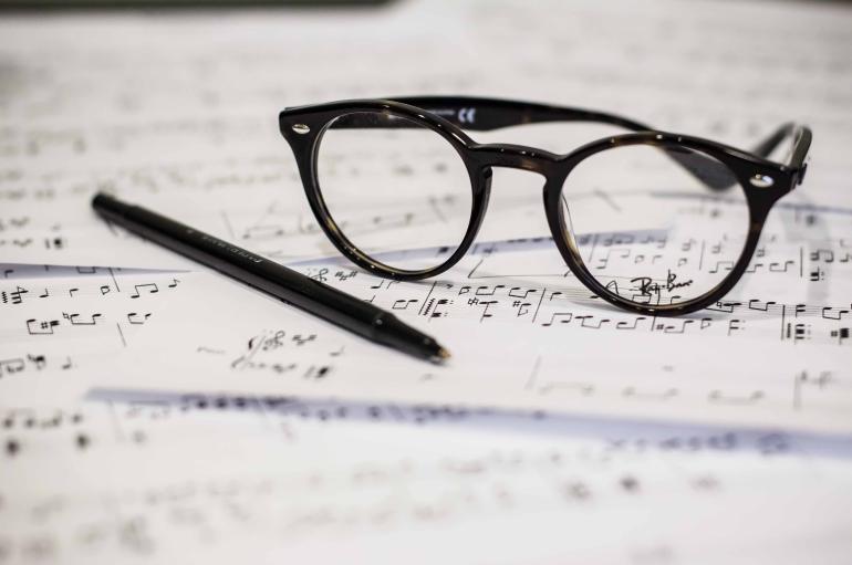 a pair of glasses and a pen resting on a musical score