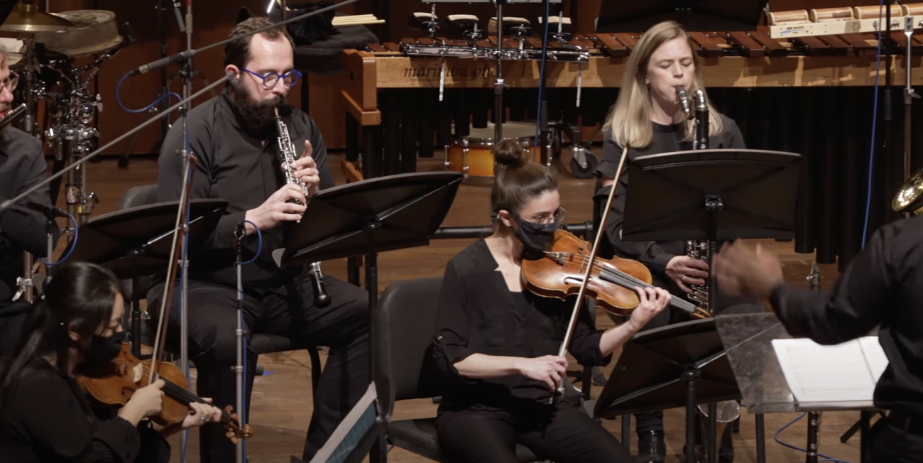 Andy Nogal playing oboe and Katie Jimoh playing clarinet with violinists in the foreground
