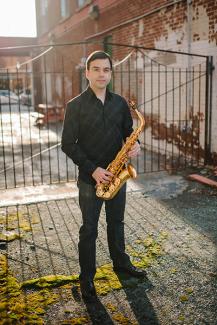 Taimur Sullivan posing outside with a saxophone