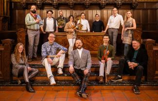 Grossman Ensemble musicians posed in the University of Chicago's Bond Chapel, some people holding instruments, some people sitting, and some standing 