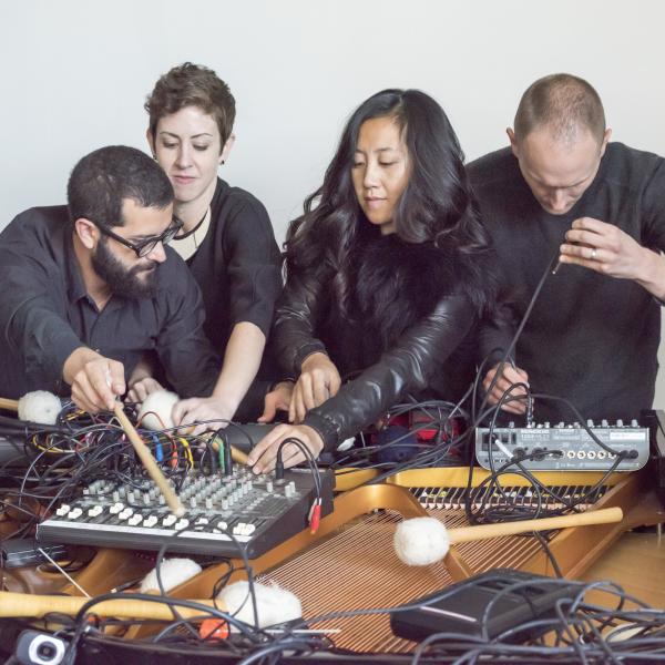 Yarn/Wire – Two men and two women lean over an open grand piano fighting over objects strewn across the stings, including electronics and percussion mallets